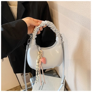 Detail of light blue crescent bag with ruched handle and pink heart charm accessory