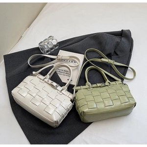 Detail of woven faux leather bag with buckle strap and adjustable shoulder strap