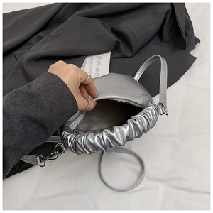 Detail of silver cloud handbag featuring metallic pleated handles and fabric lining interior