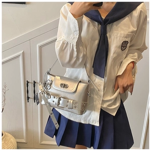 Gros plan du sac bandoulière argenté avec ceinture à œillets et fermoir rotatif métal