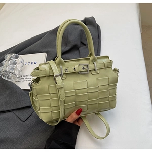 Detail of pistachio green woven leather handbag with silver buckle and crossbody strap