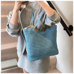 Detail of light blue woven tote bag showing crochet texture and slim leather strap