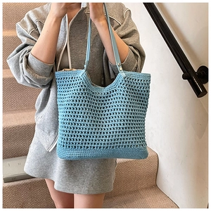 Close-up of blue crochet woven tote bag with light blue leather strap and metal rivets