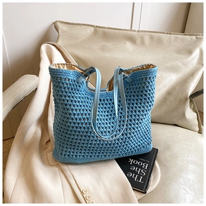 Detail of light blue crochet knit tote bag with mesh texture and slim leather strap