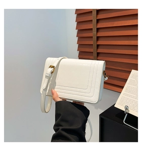 Detail of white PU leather crossbody bag with triple U-shaped stitching and golden buckle