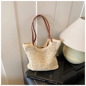 Close-up of beige crochet woven tote bag with dark brown leather straps and silver rivets