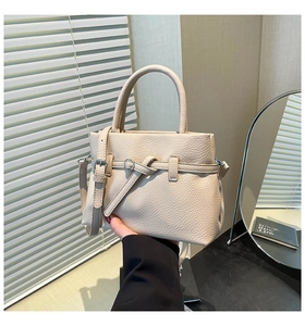 Detailed macro view of the cream lychee grain leather handbag with stylish metal buckle strap