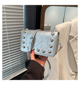 Detail of silver leather crossbody bag featuring metal studs and diamond stitching