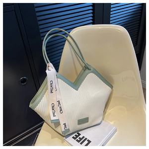 Détails rapprochés des rayures verticales et des finitions en cuir vert du sac cabas