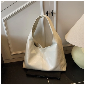Détail d'un grand sac Hobo crème présentant une texture en cuir verni brillant plissé