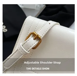 Detail of adjustable white embossed shoulder strap with vintage gold buckle on a handbag