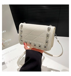 Detailed view of white rectangular crossbody bag with silver studs and geometric stitching
