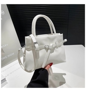 Detail of white lychee pattern leather handbag with silver metal buckle and dual handles
