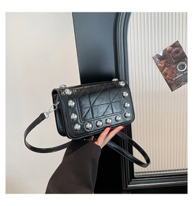 Detail of black faux leather bag with silver rivets and quilted geometric pattern