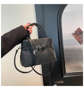 Close-up of black lychee grain leather tote bag with silver buckle and belt detail