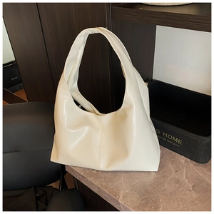 Détail du sac hobo en cuir PU brillant blanc crème posé sur une surface en marbre