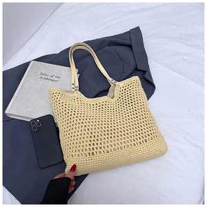 Detail of beige woven tote bag showing crochet texture and faux leather straps with books