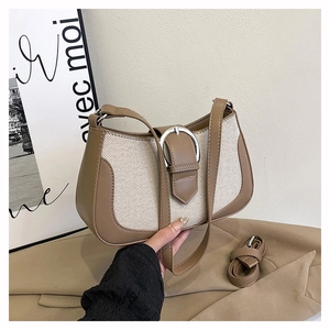 Detail of minimalist khaki and canvas shoulder bag with silver horseshoe buckle decoration