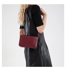 Deep red quilted crossbody bag shown on model wearing a black leather outfit