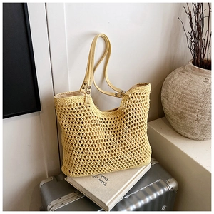 Detailed view of woven straw tote bag texture with reinforced leather shoulder straps
