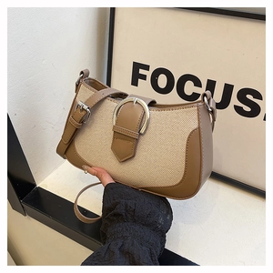 Detail of a brown patchwork shoulder bag featuring woven canvas and a large metal buckle