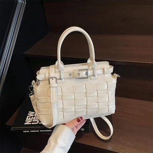 Creamy white hand-woven leather crossbody bag with top handle on a wooden staircase