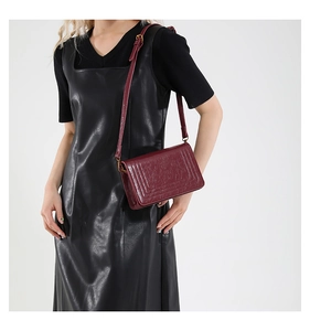 Detail of burgundy faux leather crossbody bag with vintage texture and adjustable strap