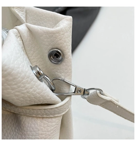 Detail of white lychee leather texture with silver metal snap and shoulder strap hook