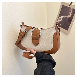 Detail of canvas and brown leather shoulder bag with large circular silver metal buckle