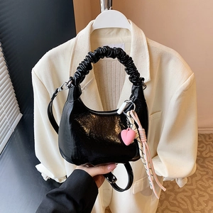Black glossy patent leather crescent shoulder bag with pleated handle and heart charm