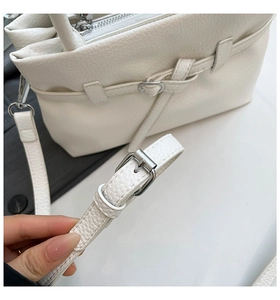 Detail of white lychee leather handbag with silver zipper and adjustable strap buckle