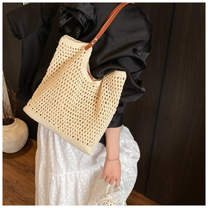 Close-up of beige hollow-out woven shoulder bag with brown leather strap and rivets