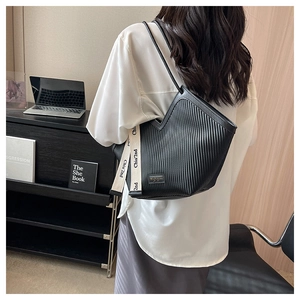 Détail d'un sac cabas noir à texture verticale avec une sangle tissée décorative
