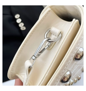 Close-up of cream square bag showing silver metal swivel hook and fine stitching detail