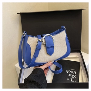 Detail of blue leather and beige fabric patchwork shoulder bag with large silver buckle