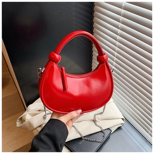 Detail of red crescent bag featuring knotted top handle and silver chain strap