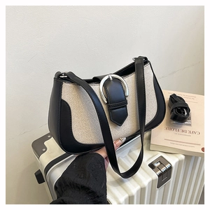 Detail of canvas bag with black leather trim, silver buckle and adjustable shoulder strap