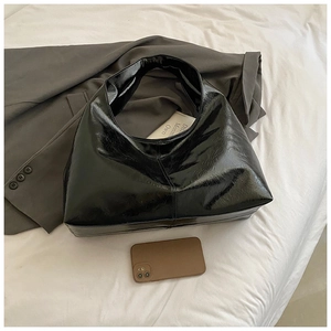 Gros plan d'un grand sac bandoulière noir brillant montrant son espace avec un smartphone