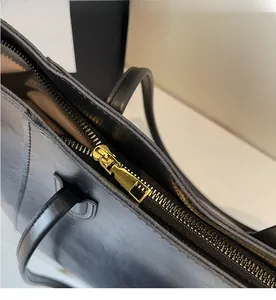 Detail of high-quality smooth gold metal zipper on minimalist black leather tote bag