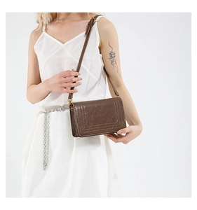 Side view of brown faux leather crossbody bag with geometric stitching and gold hardware