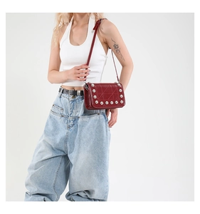 Borsa a tracolla rossa vintage con borchie argentate e cuciture su una modella