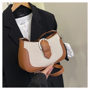 Detail of crossbody bag with brown leather, beige canvas, and silver horseshoe buckle