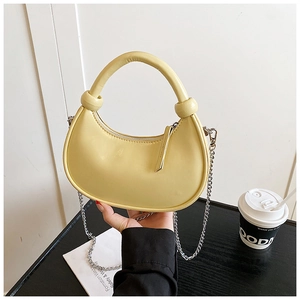 Detail of pale yellow crescent handbag with smooth PU leather and silver metal chain