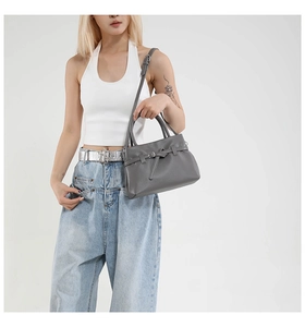 Detail of dark grey lychee pattern leather handbag with adjustable strap and metal buckle