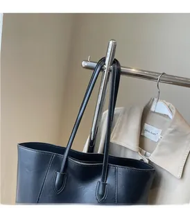 Close-up of black tote bag featuring lychee texture leather and durable zipper detail