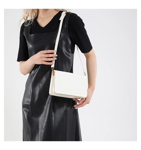 Detail of white leather shoulder bag with adjustable strap and gold metal hardware
