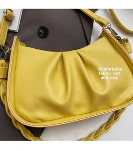 Close-up of bright yellow pleated crescent bag with soft fabric and woven handle