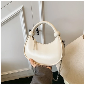Detail of creamy white crescent handbag featuring sleek PU leather and silver chain strap