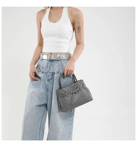 Detail of grey lychee pattern leather handbag with silver buckle and belt decoration