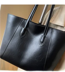 Detail of high-quality black faux leather texture and sturdy handle stitching on tote bag